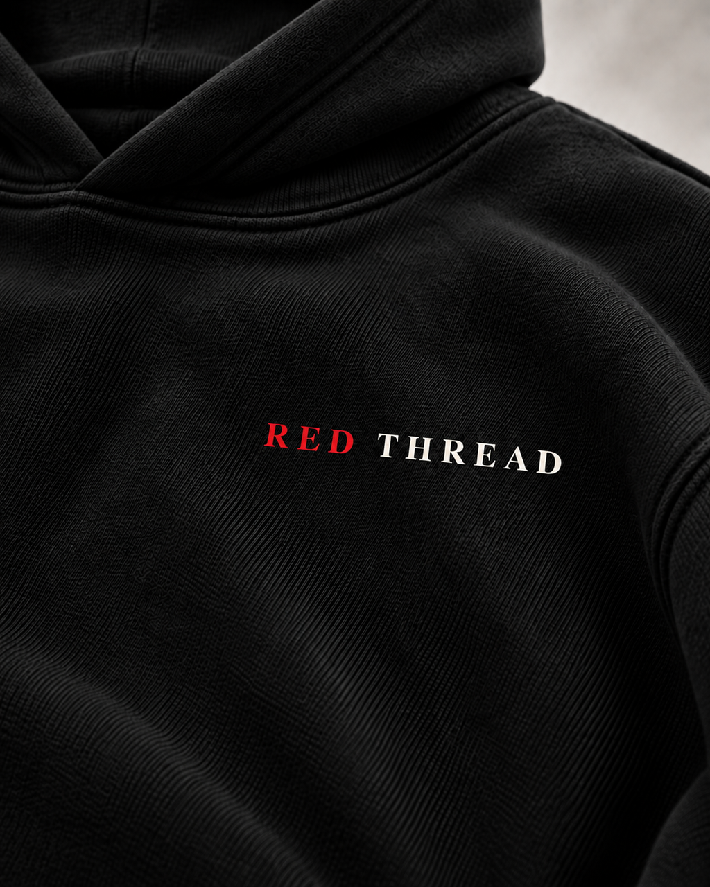 Close-up of a black hooded sweatshirt with the words 'RED THREAD' printed across the chest